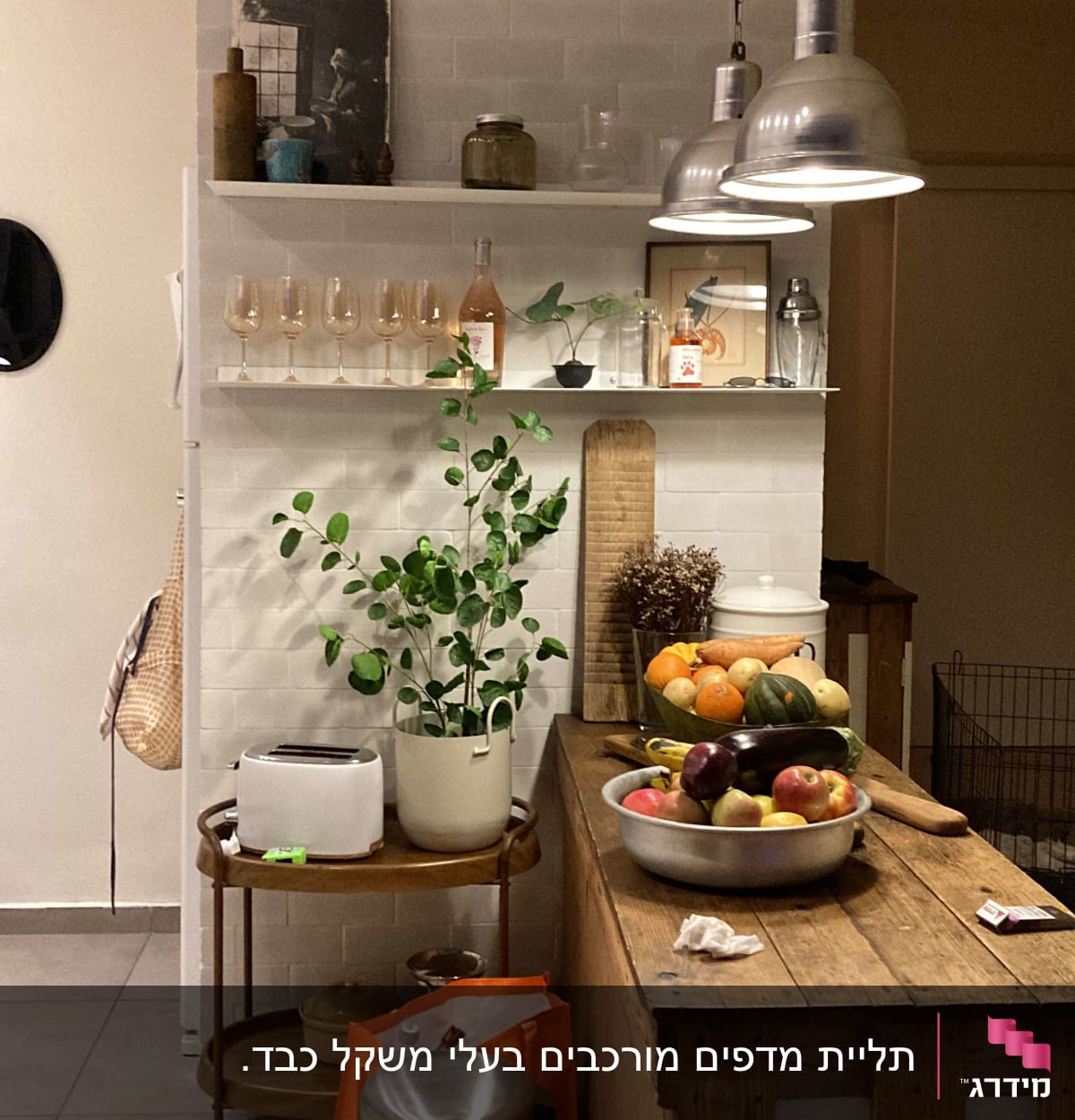 מטבח עם מדף כלים, פירות על השולחן, תאורה תלויה